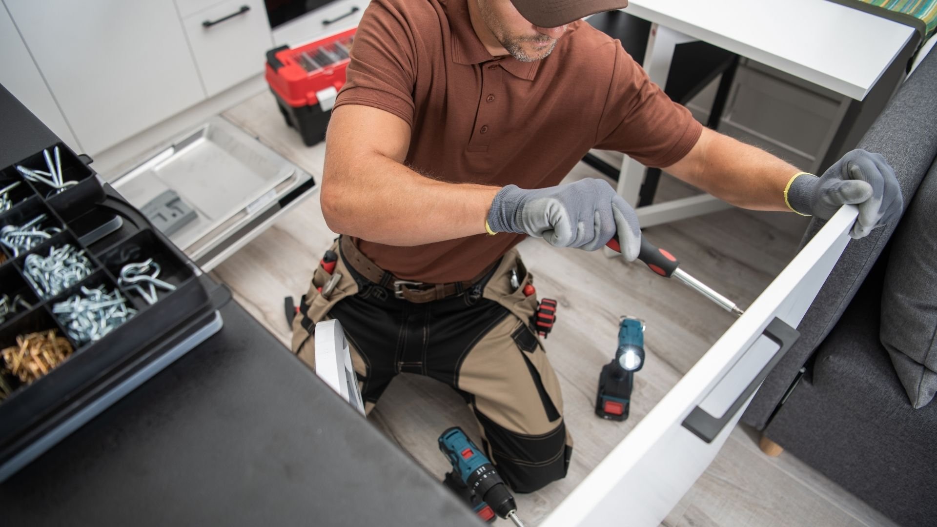 Handyman wearing work gloves organizing tools in a drawer at workbench